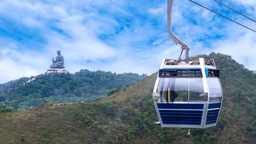 Hong Kong cable car over green mountain with Giant Buddha statue at Tian Tan, Po Lin monastery, Ngong Ping, Hong Kong city